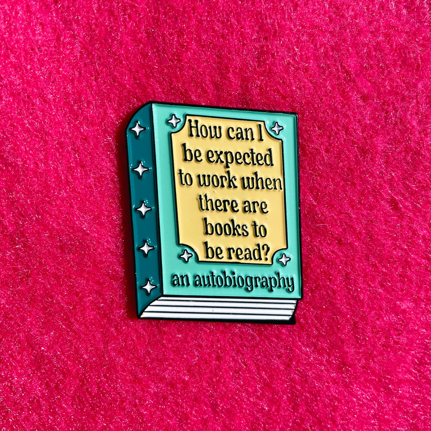 Book-shaped enamel pin with humorous quote on a pink background