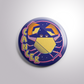 Button badge with a zodiac cancer design on a light gray background